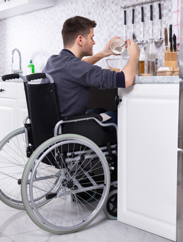 A Disabled Man Preparing Food In Kitchen — Disability Services & Support in Rockhampton, QLD