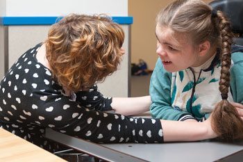 A Woman in A Wheelchair Kindly Helping a Young Girl with Her Hair — Point Care Pty Ltd in Gladstone, QLD