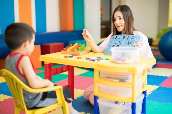 Kindergarten Teacher Helping Child Learn — Disability Services in Toowoomba, QLD