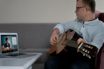 Adult Caucasian Man With Down Syndrome Learning How To Play At Guitar — Disability Services & Support in Loganholme, QLD