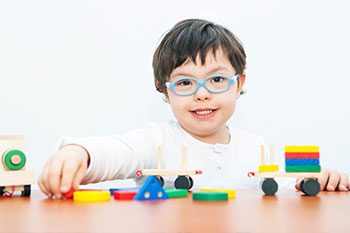 Boy With Down Syndrome Playing With Wooden Train — Disability Services & Support in Brisbane, QLD