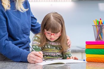 Care Giver Teaches Girl With Down Syndrome How To Write — Disability Services & Support in Caboolture, QLD