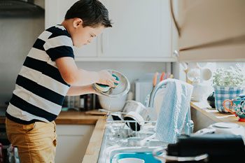 Child With Autism Doing The Dishes — Disability Services & Support in Maroochydore, QLD