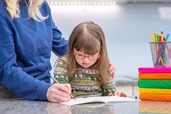 Girl With Down Syndrome Studies WIth Her Teacher — Disability Services & Support in Brisbane, QLD