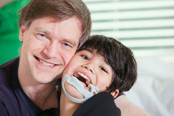 Handsome Father Holding Disabled Seven Year Old Son — Disability Services & Support in Ipswich, QLD