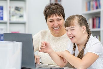 Teacher Teaches Girl With Down Syndrome Uses Laptop — Disability Services & Support in Gympie, QLD