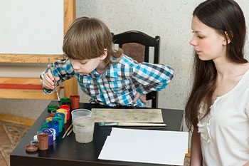 Teacher Teaching Kid With Autism How To Paint — Disability Services & Support in Nambour, QLD