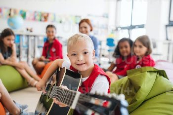 Young Child With Down Syndrome Holding A Guitar — Disability Services & Support in Maroochydore, QLD