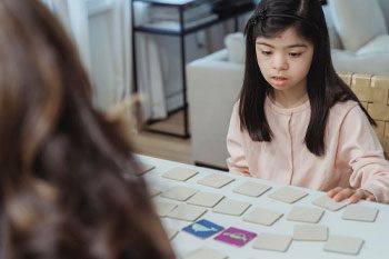 Young Girl Playing With Cards On The Table  — Disability Services & Support in Gympie, QLD